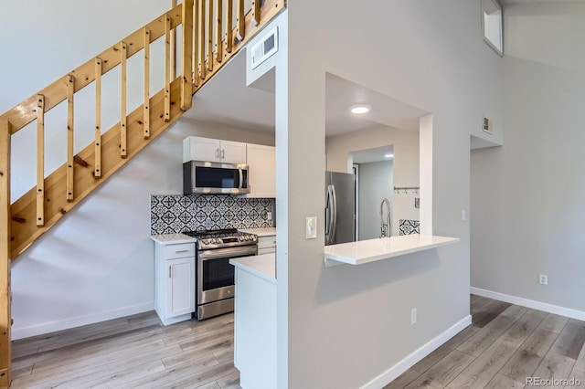 3539 S Fairplay Way Unit 10, Aurora, CO 80014 - kitchen featuring appliances with stainless steel finishes, light wood-style flooring, white cabinets, baseboards, and a high ceiling