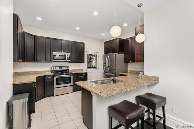 kitchen featuring sink, stainless steel appliances, kitchen peninsula, pendant lighting, and a breakfast bar