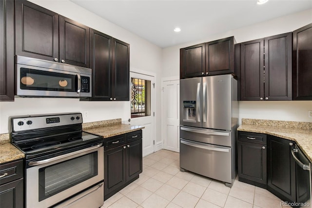 kitchen with dark brown cabinets, light stone countertops, stainless steel appliances, and light tile patterned floors