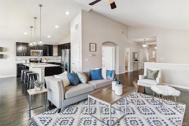 living area featuring arched walkways, visible vents, baseboards, and wood finished floors