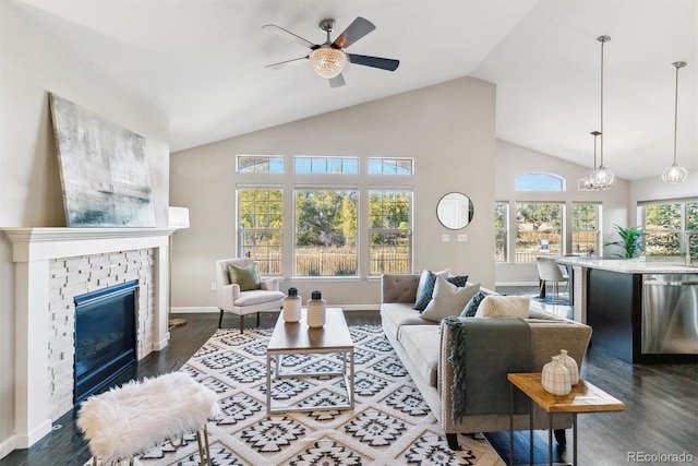 living room featuring dark wood-style floors, a brick fireplace, high vaulted ceiling, baseboards, and ceiling fan with notable chandelier