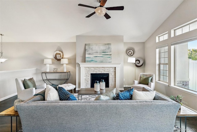 living room with baseboards, a ceiling fan, a glass covered fireplace, dark wood-style flooring, and vaulted ceiling