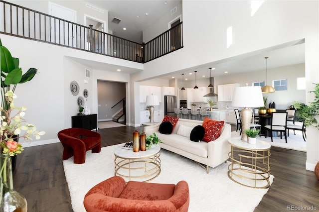 living room with a towering ceiling and dark hardwood / wood-style flooring