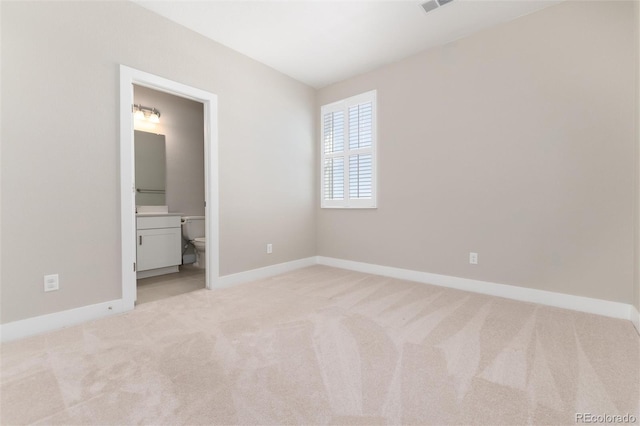 unfurnished bedroom with ensuite bathroom and light carpet