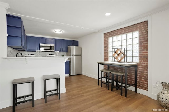 3047 W 47th Ave Unit 607, Denver, CO 80211 - kitchen featuring appliances with stainless steel finishes, blue cabinets, open shelves, a breakfast bar area, and wood finished floors