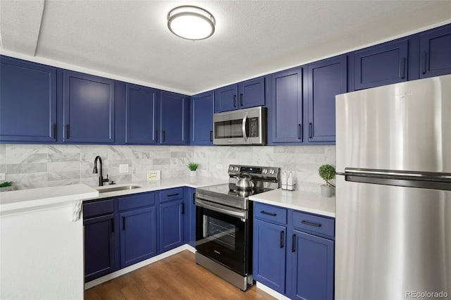 3047 W 47th Ave Unit 607, Denver, CO 80211 - kitchen with stainless steel appliances, blue cabinets, a sink, and light countertops