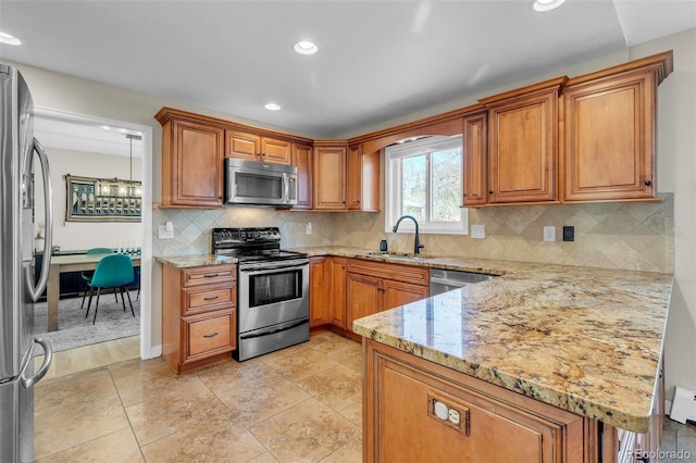 3730 Applewood St, Grand Junction, CO 81506 - kitchen with light stone countertops, brown cabinetry, a peninsula, appliances with stainless steel finishes, and a sink