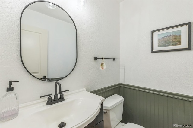 3730 Applewood St, Grand Junction, CO 81506 - bathroom featuring a textured wall, toilet, vanity, and a wainscoted wall