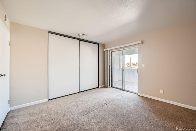 unfurnished bedroom with access to outside, a closet, and carpet flooring