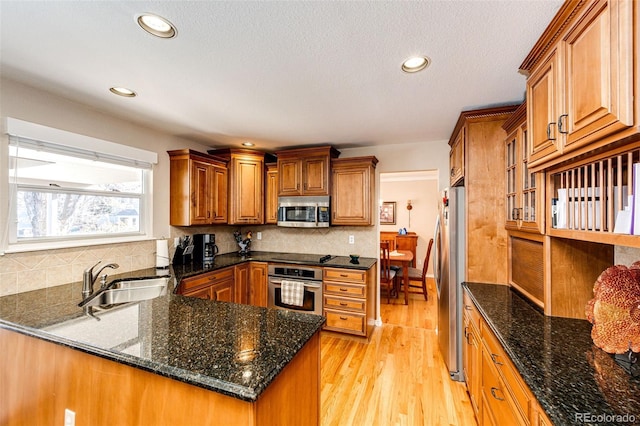 6454 S Nelson Way, Littleton, CO 80127 - kitchen featuring a sink, appliances with stainless steel finishes, brown cabinetry, light wood finished floors, and a peninsula
