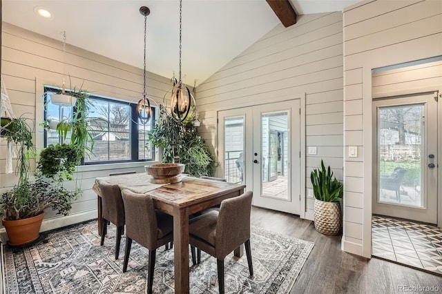 dining room featuring wooden walls, beam ceiling, a chandelier, french doors, and wood finished floors