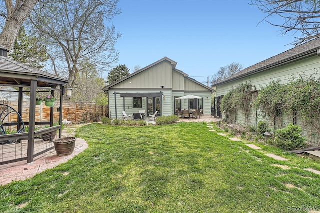 back of property featuring a lawn, board and batten siding, a patio area, and a fenced backyard