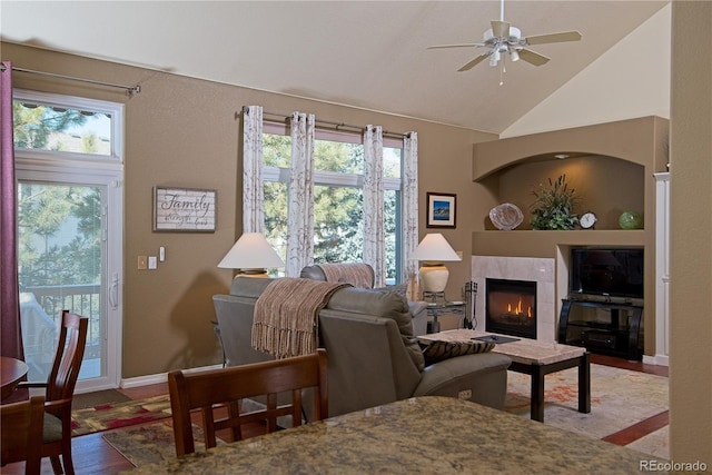 living room featuring high vaulted ceiling, a fireplace, light hardwood / wood-style floors, and ceiling fan