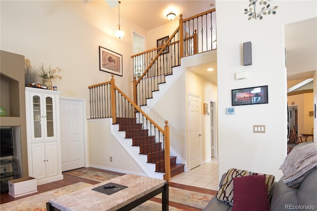 stairway with a towering ceiling and tile patterned floors