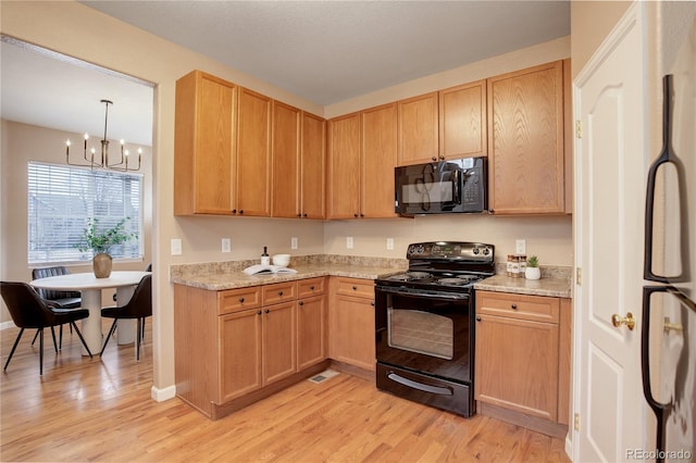 kitchen featuring light wood finished floors, a notable chandelier, black appliances, and light brown cabinetry