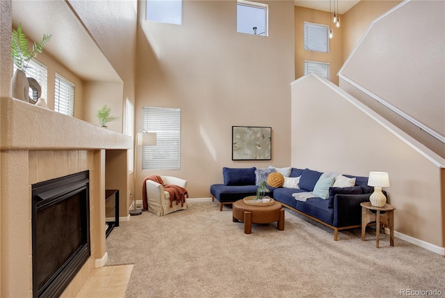 living room featuring a high ceiling, a fireplace, baseboards, and light carpet