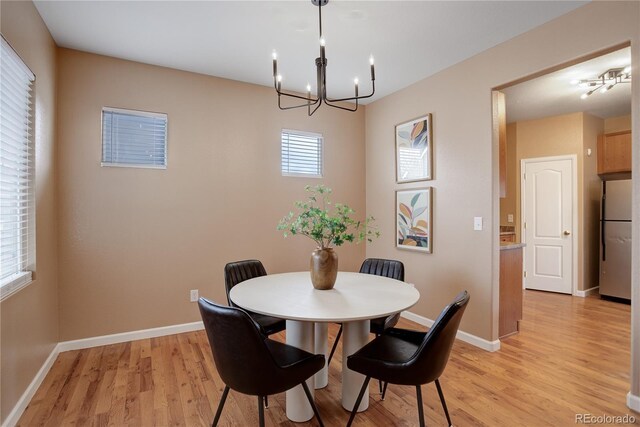 dining space featuring baseboards, light wood-type flooring, and a chandelier