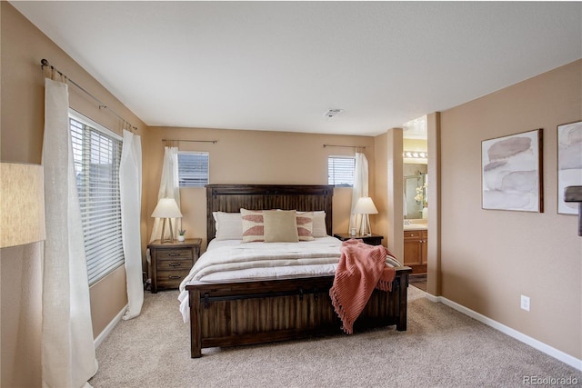 bedroom featuring light colored carpet, baseboards, and connected bathroom