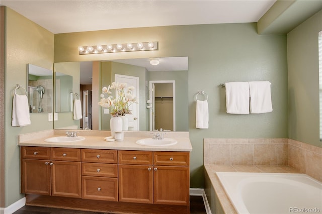 full bathroom featuring double vanity, a bath, baseboards, and a sink