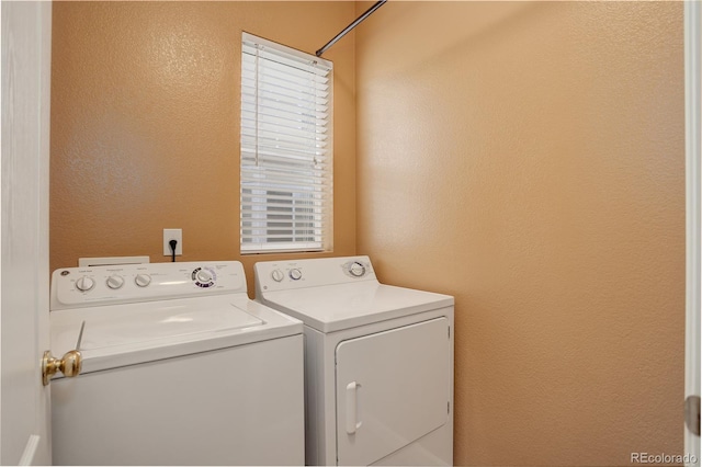 clothes washing area with laundry area, washing machine and dryer, and a textured wall