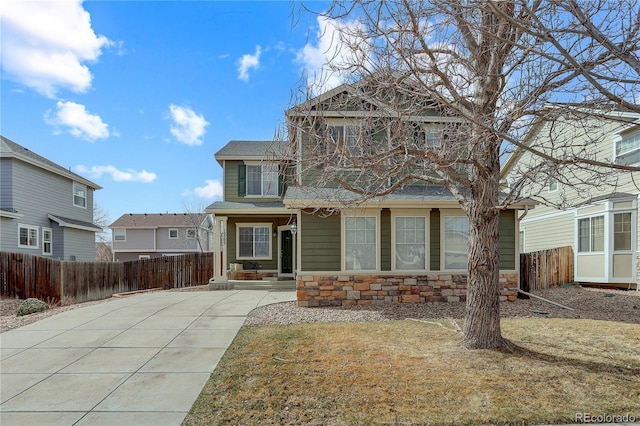 rear view of house with stone siding and fence