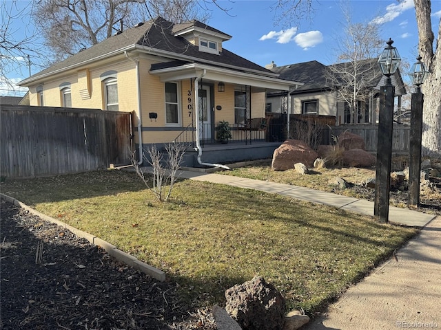 bungalow featuring a porch, fence, and a front lawn