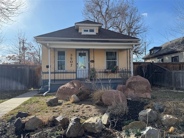 view of front of property with roof with shingles, covered porch, and fence