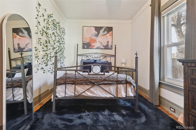 bedroom featuring crown molding, wood finished floors, and baseboards