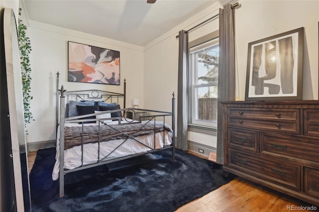 bedroom with baseboards, wood finished floors, and ornamental molding