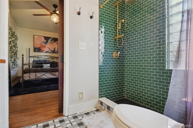 full bathroom with wood finished floors, baseboards, tiled shower, ceiling fan, and toilet