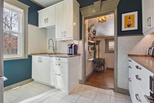 kitchen featuring a chandelier, light tile patterned floors, white cabinetry, and a sink