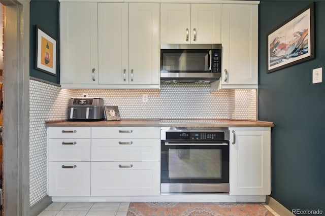 kitchen with cooktop, white cabinets, wall oven, stainless steel microwave, and backsplash