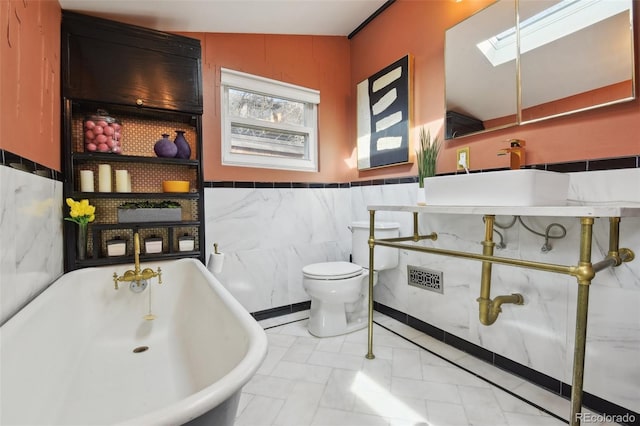 full bathroom with baseboard heating, toilet, a skylight, wainscoting, and a freestanding bath