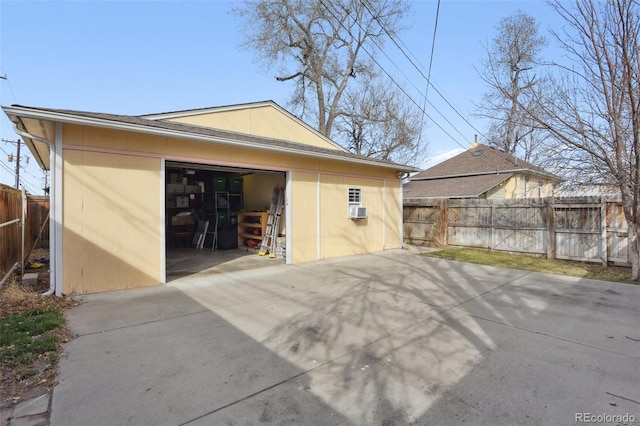 garage featuring cooling unit, driveway, and fence