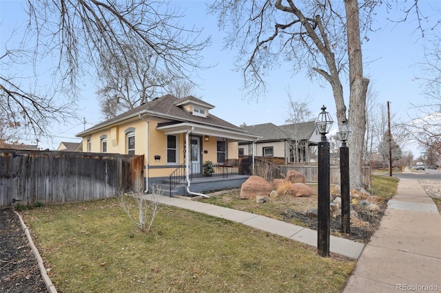 bungalow with a porch, a front yard, and fence