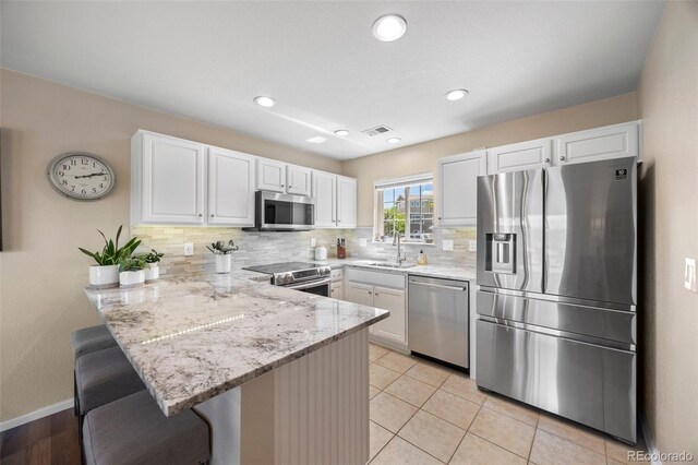 4194 Beautiful Cir, Castle Rock, CO 80109 - kitchen with appliances with stainless steel finishes, a sink, a peninsula, white cabinetry, and light stone counters