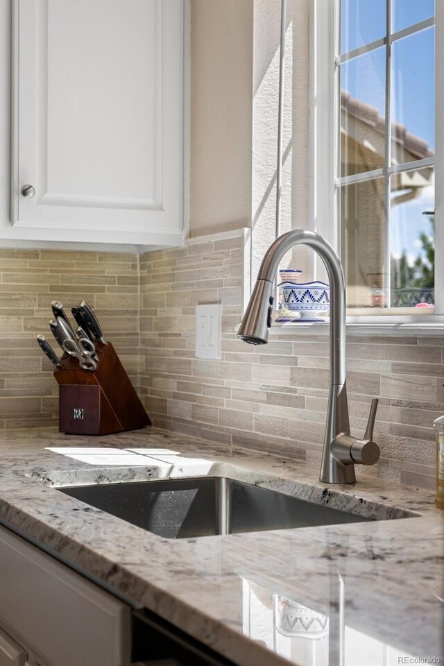 4194 Beautiful Cir, Castle Rock, CO 80109 - kitchen view of a sink, white cabinets, backsplash, and light stone countertops