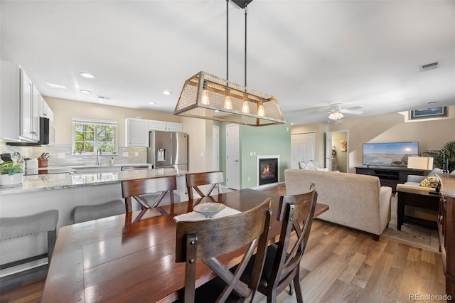 4194 Beautiful Cir, Castle Rock, CO 80109 - dining space with a glass covered fireplace, ceiling fan, wood finished floors, and recessed lighting