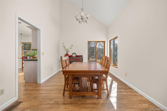 6868 Johnson St, Arvada, CO 80004 - dining area with a chandelier, wood finished floors, high vaulted ceiling, and baseboards