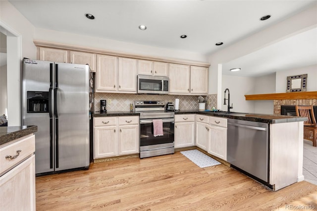 6868 Johnson St, Arvada, CO 80004 - kitchen featuring appliances with stainless steel finishes, a sink, a peninsula, light wood-style flooring, and dark countertops