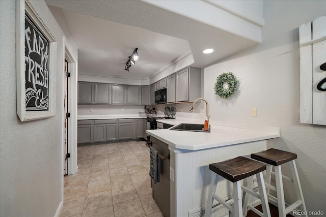 5107 Pasadena Way, Broomfield, CO 80023 - kitchen featuring gray cabinets, black appliances, a peninsula, light countertops, and a kitchen bar