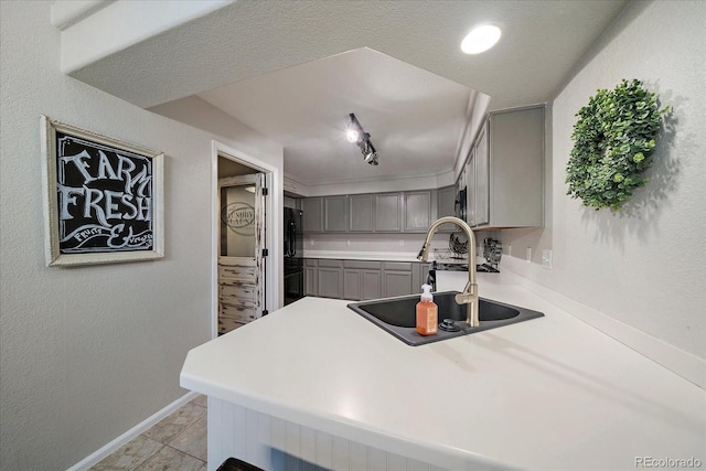 5107 Pasadena Way, Broomfield, CO 80023 - kitchen featuring gray cabinetry, light countertops, a peninsula, black fridge, and a textured wall