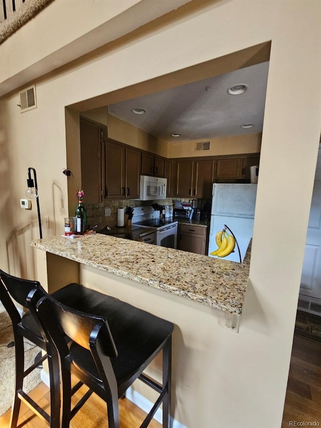 6711 S Ivy Way Unit B5, Centennial, CO 80112 - kitchen with white appliances, dark brown cabinetry, tasteful backsplash, a peninsula, and recessed lighting
