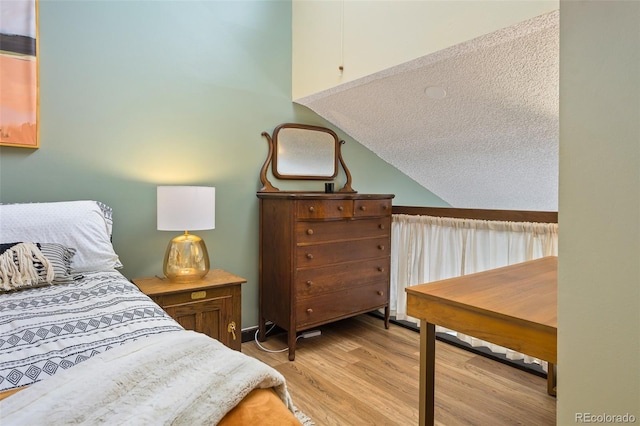 bedroom featuring lofted ceiling and light hardwood / wood-style flooring