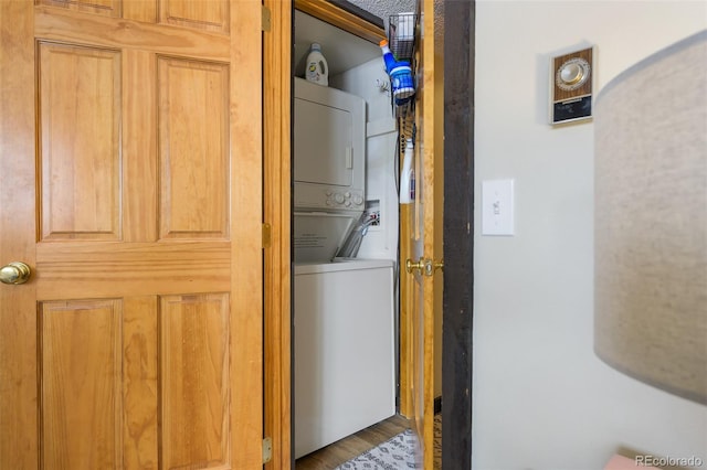 laundry area featuring stacked washing maching and dryer and wood-type flooring