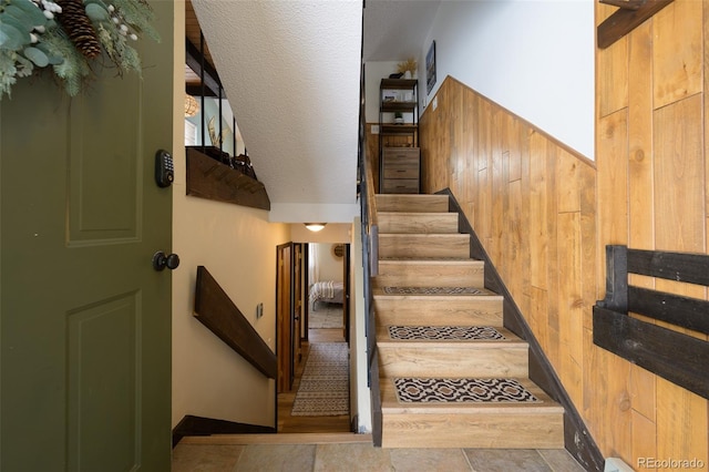 staircase featuring wooden walls