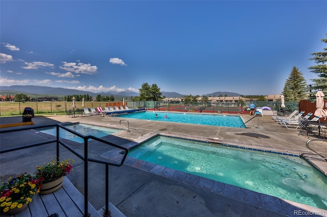 view of swimming pool featuring a patio, a hot tub, and a mountain view