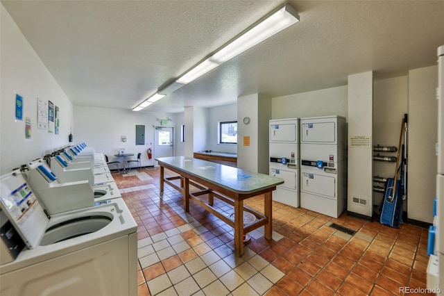 kitchen with stacked washing maching and dryer, a textured ceiling, electric panel, tile patterned floors, and white cabinets