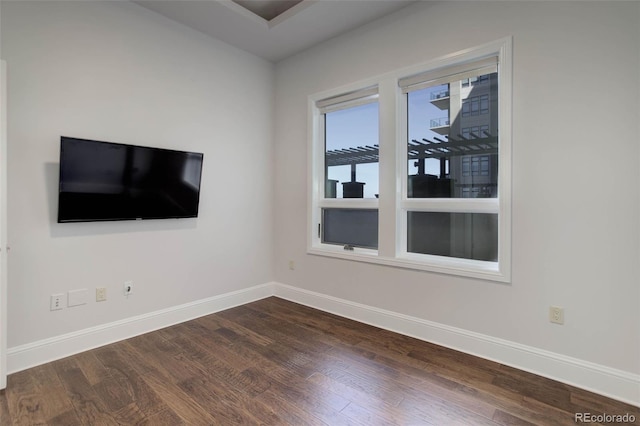 spare room featuring baseboards and dark wood-style flooring