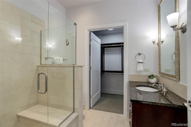 full bath featuring a shower stall, a spacious closet, vanity, and tile patterned flooring